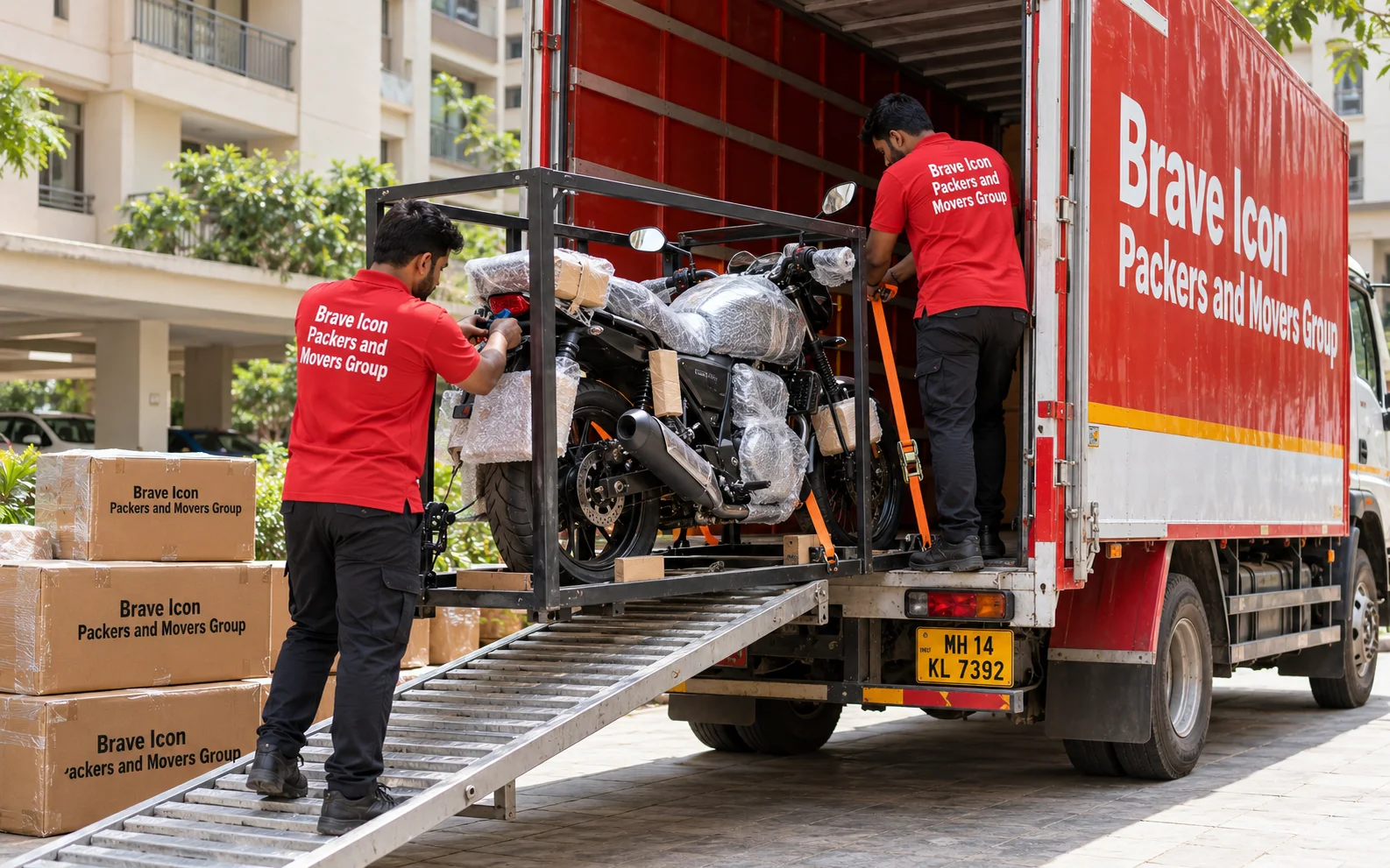 Movers secure a protected motorcycle in a transport frame inside a red-and-white carrier truck in Noida.